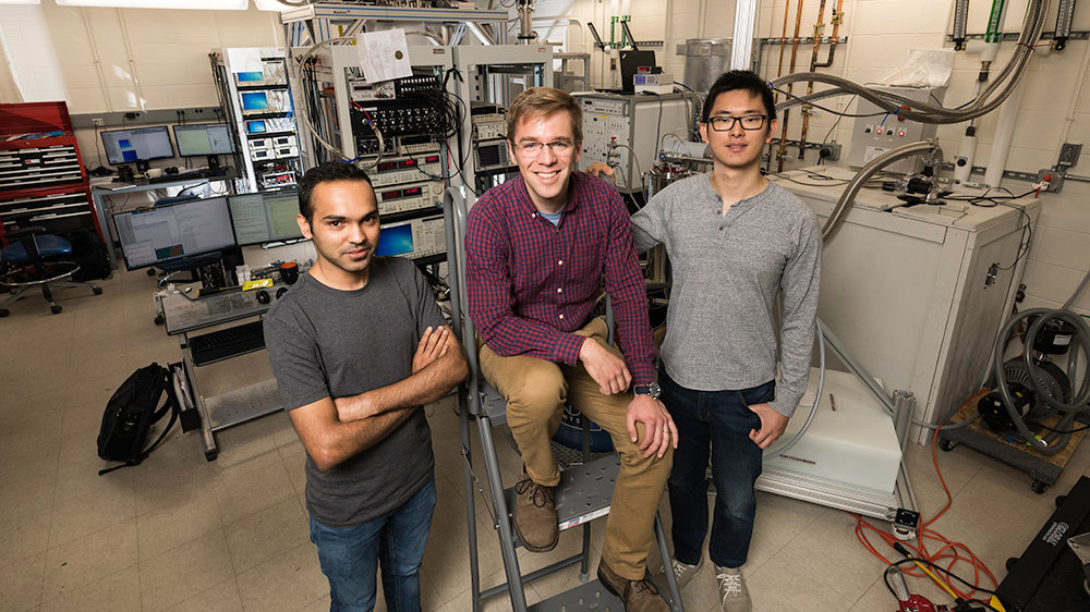 John Nichol and PhD students Yadav Kandel, left, and Haifeng Qiao, right, demonstrated a way to manipulate electrons and transmit information quantum-mechanically, bringing scientists one step closer to creating a fully functional quantum computer. Quantum computers will be able to perform complex calculations, factor extremely large numbers, and simulate the behaviors of atoms and particles at levels that classical computers cannot. (University of Rochester photo / J. Adam Fenster) John Nichol and PhD students Yadav Kandel, left, and Haifeng Qiao, right, demonstrated a way to manipulate electrons and transmit information quantum-mechanically, bringing scientists one step closer to creating a fully functional quantum computer. Quantum computers will be able to perform complex calculations, factor extremely large numbers, and simulate the behaviors of atoms and particles at levels that classical computers cannot. (University of Rochester photo / J. Adam Fenster)
