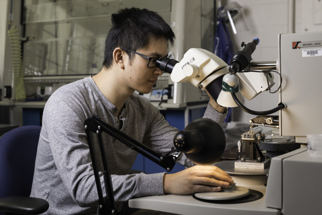 Doctoral student Haifeng Qiao uses a wire bonder to make electrical contact between the circuit board and the experimental device. (University of Rochester photo / J. Adam Fenster)